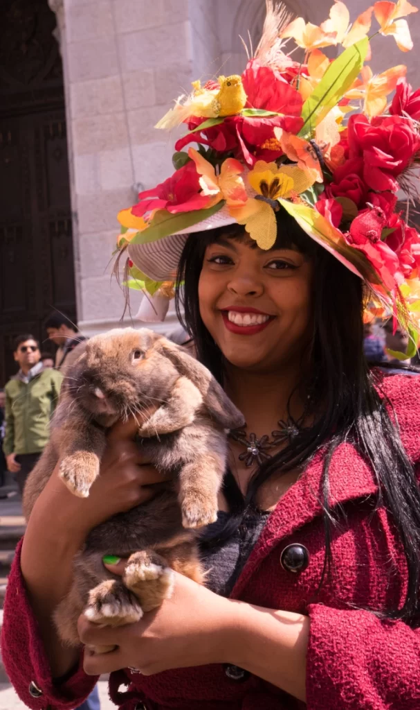Young woman in a big flowered hat with her pet rabbit at the Easter Parade on Fifth Avenue in New York City,