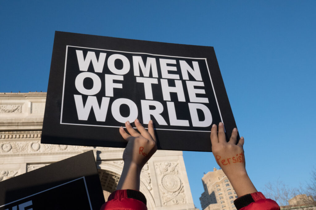 Women of the World sign held up in Washington Square Park.