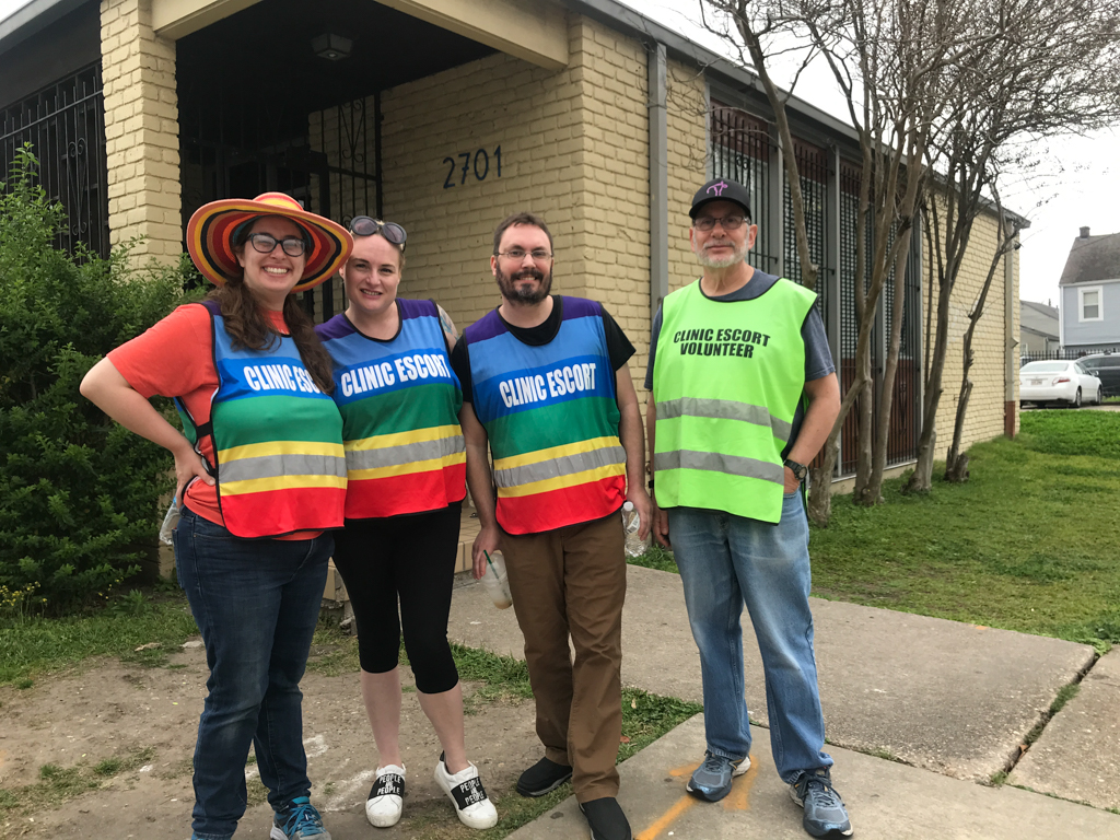 Clinic Escorts accompany abortion seekers into the clinic in New Orleans past noisy protesters (nearby but not pictured), 2019