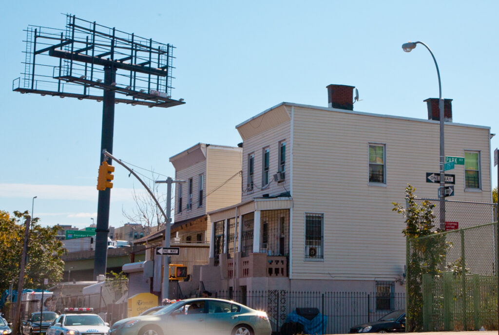 Houses and billboard frame abut the Cross-Bronx Expressway at 175th St. and Park Ave., Bathgate neighborhood, Bronx, NY. Photo by Pat Arnow Irv moved to this block when he was four, in 1922. Today there's a chain link fence where a four-story tenement used to stand.